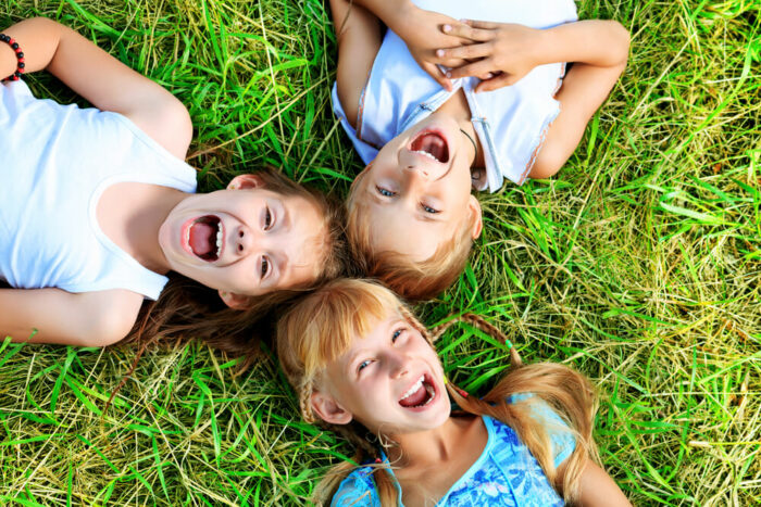 Three cute kids on the grass and laughing