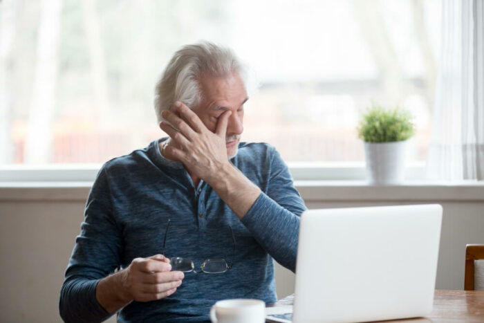 Older man rubbing his eye after taking off his glasses