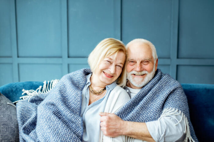 Mature couple wrapped up in a blue blanket in blue room