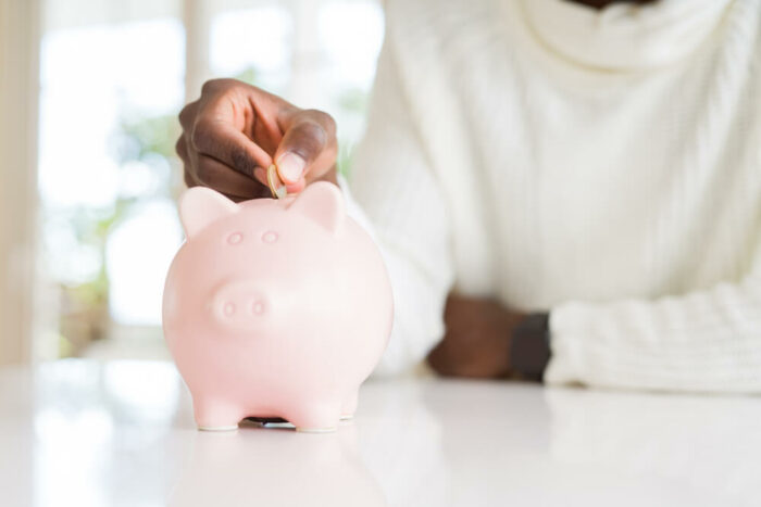 woman putting a coin in a pink piggy bank